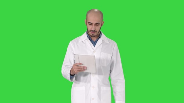 Ώριμο αρσενικό γιατρό κρατώντας το ψηφιακό δισκίο χρησιμοποιώντας το και περπατώντας σε μια πράσινη οθόνη, πλήκτρο αποχρώσεων. — Αρχείο Βίντεο