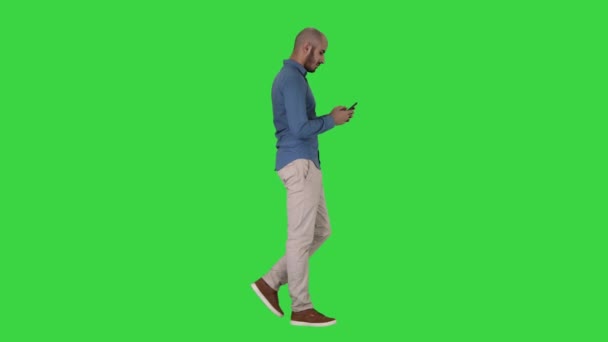 Młody człowiek chodzenia i korzystania z telefonu na zielonym ekranie, Klucz chrominancji. — Wideo stockowe