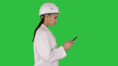 Mühendis bir yeşil ekranda Chroma Key yürürken cep telefonu manifatura kullanma.