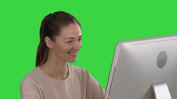 Student blonde girl looking at monitor of computer and smiling on a Green Screen, Chroma Key. — Stock Video