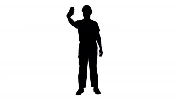Silhouette lächelt gut aussehende junge Bauarbeiter macht Selfie mit Handy. — Stockvideo