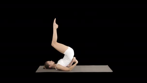 Женщина, практикующая йогу, стоящая в упражнении саламба сарвангасана, поддерживающая позу плеча, канал Альфа — стоковое видео