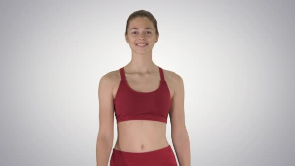 Sonriente mujer deportiva caminando y sonriendo sobre fondo degradado. — Vídeo de stock