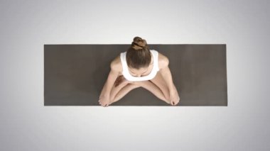 Nilüfer çiçeğinde oturmuş yoga yapan genç ve sportif bir kadın, arka planda derin bir nefes alıyor..