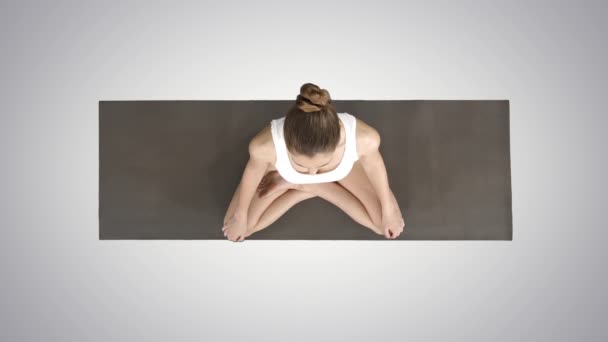 Jonge sportieve vrouw die yoga beoefent zittend in lotushouding en diep ademend op gradiënt achtergrond. — Stockvideo