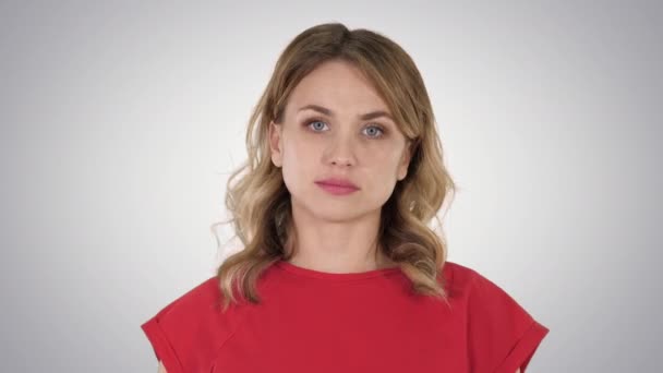 Mujer joven camiseta roja está caminando, mirando a la cámara en el fondo degradado. — Vídeos de Stock