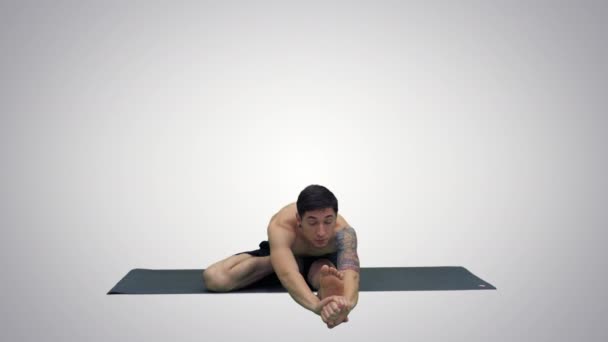 Человек в сидячей йоге Marichyasana представляет растяжение ноги и позвоночника упражнения на градиентном фоне . — стоковое видео