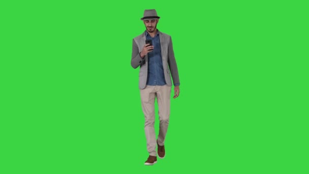 Slimme casual Arabische man met behulp van smartphone tijdens het lopen op een groen scherm, Chroma Key. — Stockvideo