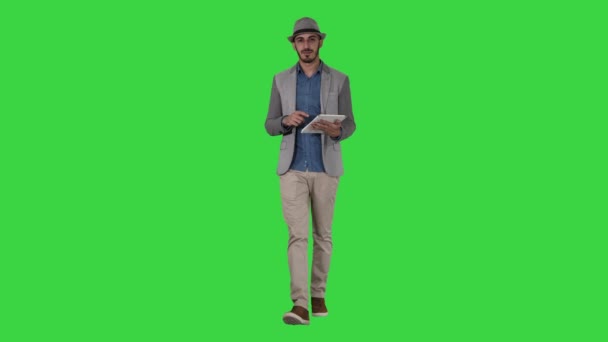 Arabisk presentatör i casual Walking med Tablet och svepa sidor på den på en grön skärm, Chroma Key. — Stockvideo