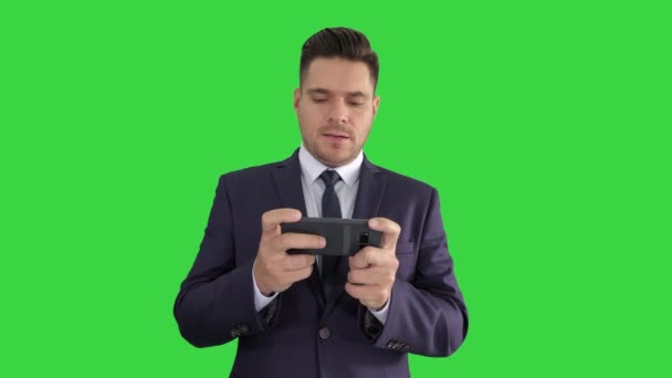 Όμορφος επιχειρηματίας παίζοντας με το smartphone του και χάνοντας σε μια πράσινη οθόνη, πλήκτρο αποχρώσεων. — Αρχείο Βίντεο