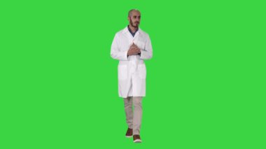 Orta yaş doktor adam tıbbi üniforma sunan giyen ve avuç içi ile yeşil ekranda kameraya bakarak işaret, Chroma Key.