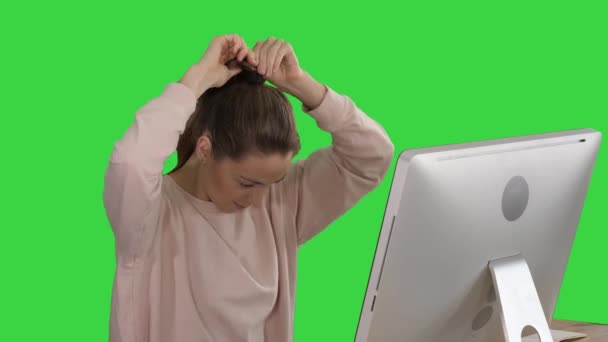 Κυρία γραφείο σε ροζ πουλόβερ με ένα πόνυ ουρά μαλλιά που εργάζονται στον υπολογιστή σε μια πράσινη οθόνη, χρώμα αποχρώσεων. — Αρχείο Βίντεο