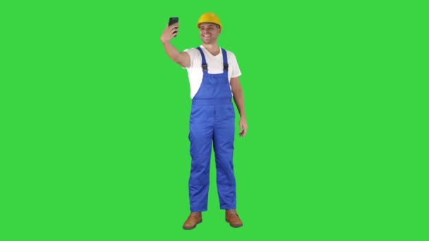Χαμογελαστός όμορφος νεαρός οικοδόμος φτιάχνοντας selfie με κινητό τηλέφωνο σε μια πράσινη οθόνη, πλήκτρο αποχρώσεων. — Αρχείο Βίντεο