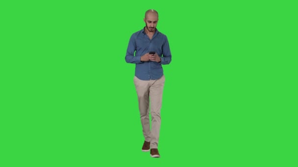 Mensajería de texto del hombre mientras camina en una pantalla verde, Chroma Key . — Vídeo de stock