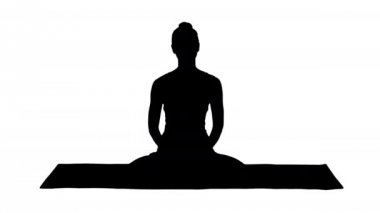 Siluet. Beyaz elbiseli güzel kadın yoga minderinde oturup kamerayla konuşuyor..