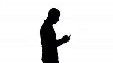Siluet Genç adam yürüyor ve telefon kullanıyor.