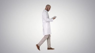 Doktor degrade arka planda yürürken tabletini kontrol.