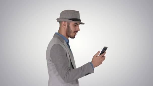 Чоловік ходить з телефоном і кріпиться в Інтернеті на градієнтному фоні . — стокове відео