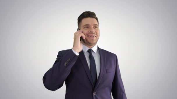 Улыбающийся молодой бизнесмен разговаривает по телефону со своим мобильным на градиентном фоне . — стоковое видео