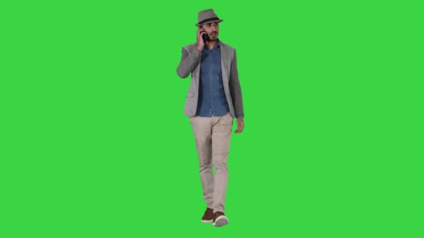 Щасливий молодий північноафриканський людина, що розмовляє на мобільному телефоні під час прогулянки по зеленому екрану, ключ кольоровості. — стокове відео