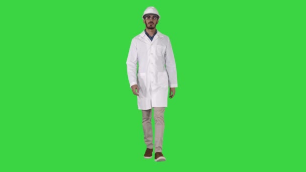 Jovem engenheiro de roupão e capacete vestindo óculos enquanto caminha em uma tela verde, Chroma Key . — Vídeo de Stock