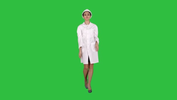 Nő mérnök fehér köntöst és a gyaloglás-ra egy zöld képernyő, Chroma Key, fehér kemény kalap. — Stock videók