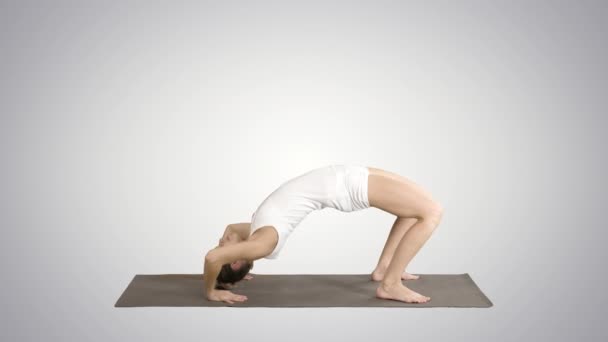 Menina de ioga esportiva realizando Chakrasana Urdva Dhanurasana Wheel Pose no fundo gradiente . — Vídeo de Stock