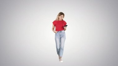 Sarışın kadın degrade arka planda yürürken onu akıllı telefon ile mesajlaşma.