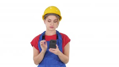 Beyaz arka planda cep telefonuyla Sert Şapka Mesajı Giyen Genç Profesyonel Kadın Müteahhit.