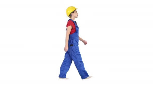 Young woman construction worker in yellow hardhat walking on white background. — 비디오