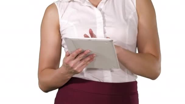 Kobieta trzymająca cyfrową tabletkę i korzystająca z niej podczas chodzenia po białym tle. — Wideo stockowe