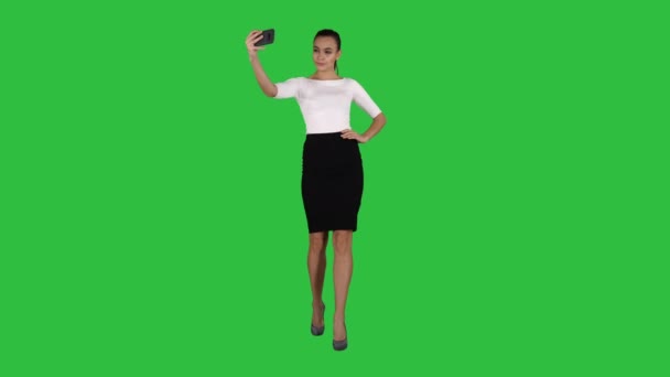 Mujer atractiva sonriente tomando una selfie mientras camina en una pantalla verde, Chroma Key . — Vídeos de Stock