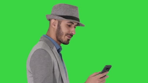 Περιστασιακή άνθρωπος μηνύματα στο τηλέφωνο και το περπάτημα σε μια πράσινη οθόνη, πλήκτρο αποχρώσεων. — Αρχείο Βίντεο