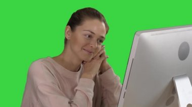 Bilgisayarda videolar izleyen ve Yeşil Ekran, Krom Anahtar 'da gülen bir kadın.