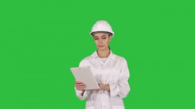 Kadın mühendisi bilgi ve onun tablet Chroma anahtar yeşil ekranda nesneleri denetleme.