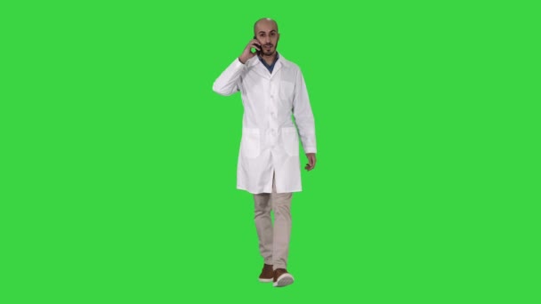 Επαγγελματίας ιατρικός γιατρός που μιλάει στο κινητό τηλέφωνο ενώ περπατάει σε μια πράσινη οθόνη, πλήκτρο αποχρώσεων. — Αρχείο Βίντεο