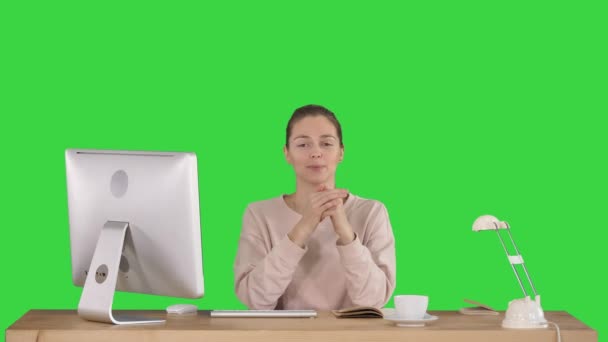 Χαμογελαστή γυναίκα που κάθεται στο γραφείο και μιλά στην κάμερα χαμογελώντας σε μια πράσινη οθόνη, πλήκτρο αποχρώσεων. — Αρχείο Βίντεο