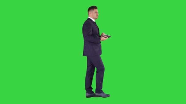 Elegante giovane uomo d'affari che utilizza il suo tablet PC mentre cammina su uno schermo verde, Chroma Key . — Video Stock