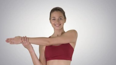 Germe egzersizleri yapmak Degrade arka planda yürürken germe egzersizleri yapan güzel genç kadın.