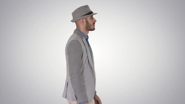 Hombre árabe casual en sombrero caminando sobre fondo degradado. — Vídeo de stock