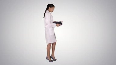 Degrade arka planda dizüstü bilgisayar yürüyüşü ve okuma ile çekici tıp öğrencisi veya doktor.