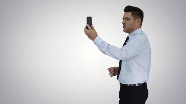 Jovem empresário bonito feliz gravando vlog ou fazendo chamada de vídeo no fundo gradiente . — Vídeo de Stock