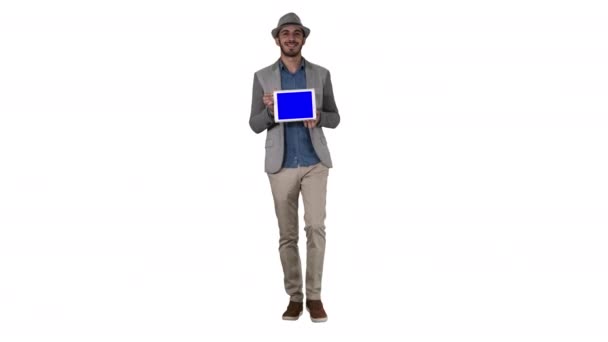 Casual man in een hoed wandelen en tonen digitale tablet naar camera op witte achtergrond. — Stockvideo