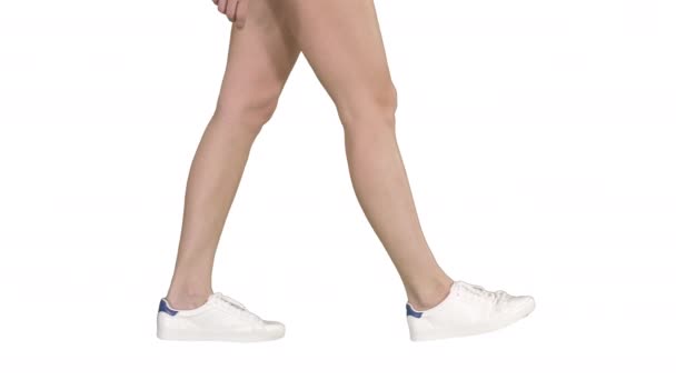 Γυναικεία πόδια φορώντας λευκά αθλητικά παπούτσια Περπάτημα σε λευκό φόντο. — Αρχείο Βίντεο