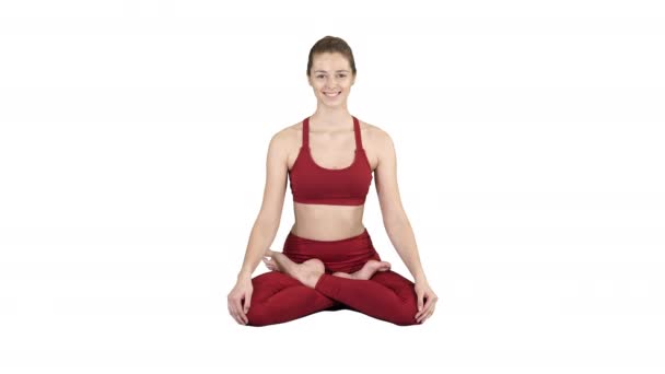 Joven mujer sonriente practicando yoga, haciendo ejercicio Padmasana, pose de loto sobre fondo blanco . — Vídeos de Stock