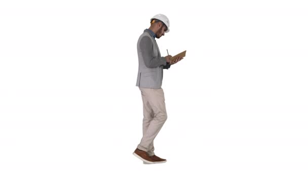 Hombre árabe en ropa casual y sombrero duro anotando lista de verificación sobre fondo blanco. — Vídeos de Stock