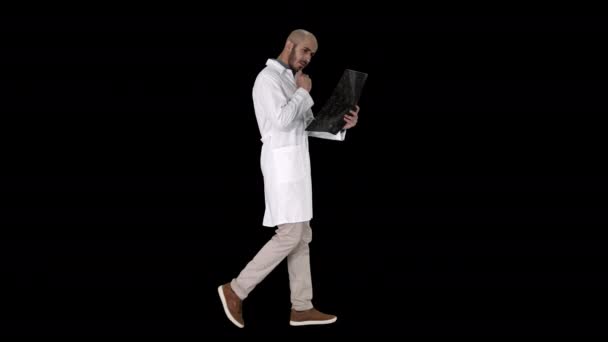 Молодой врач-мужчина читает и рассматривает МРТ мозга во время ходьбы, Альфа-канал — стоковое видео