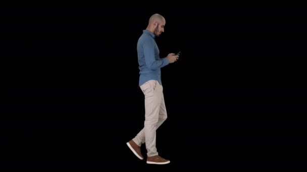 Mladý muž, který chodí a používá telefon, alfa kanál — Stock video