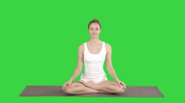 Huzurlu kadın Yoga pratik, Lotus oturan poz, yeşil ekran üzerinde boyun germe, Chroma anahtar.