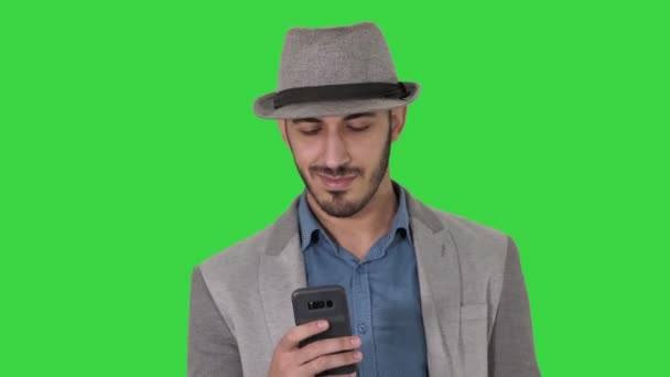 Slimme casual Arabische man met behulp van smartphone tijdens het lopen op een groen scherm, Chroma Key. — Stockvideo
